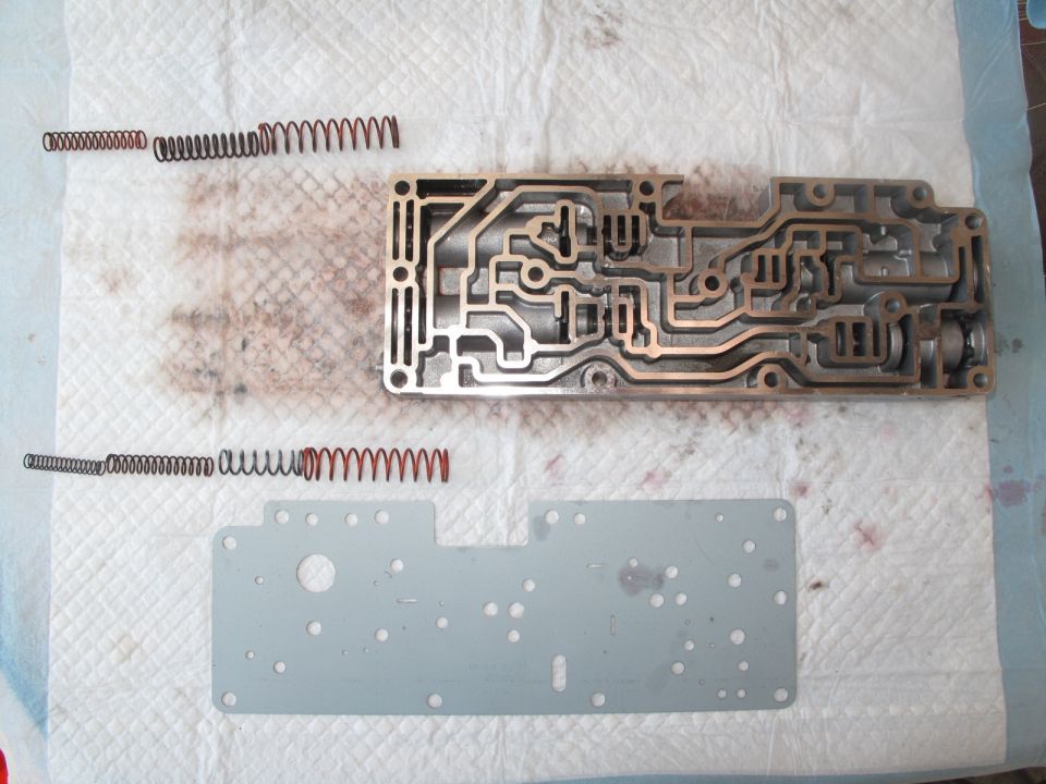 Transmission valve body and springs on paper towels. Supermotors.net logo visible