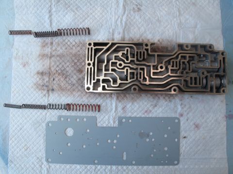 1995 Ford Bronco - Disassembled transmission valve body and springs laid out on a paper towel.