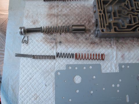 1995 Ford Bronco - Disassembled transmission valve body components, including springs and a metal plate, are laid out on a surface.