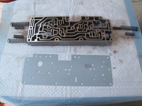 1995 Ford Bronco - Disassembled transmission valve body and gasket with springs, laid out on a surface.