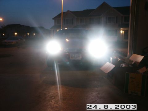 1998 Mercury Sable - A red 1998 Mercury Sable sedan is parked at dusk, its headlights illuminating the scene.