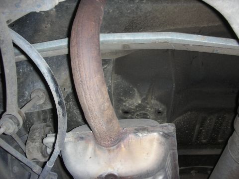 2004 Ford Crown Victoria - Close-up of the rusted exhaust system components on the underside of a vehicle.