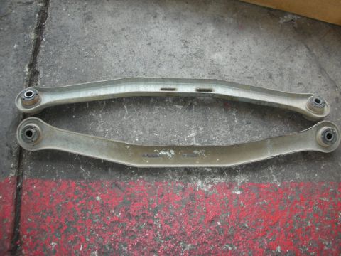 2004 Ford Crown Victoria - Two control arms are shown on a concrete surface, possibly for a vehicle suspension system.
