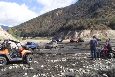1995 Ford Bronco - A group of off-road vehicles navigates a challenging muddy terrain in a scenic, mountainous area.