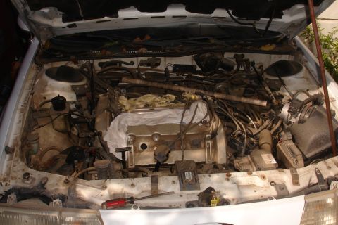 1990 Ford Taurus - The engine bay is filled with a complex network of wires and hoses, obscuring the engine itself.