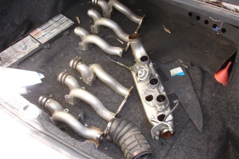 1990 Ford Taurus - Engine intake manifold parts and a rubber hose are stored in the trunk of a car.
