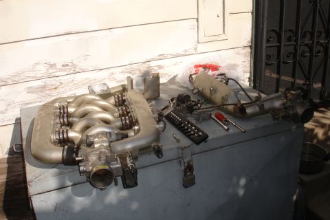1990 Ford Taurus - Engine intake manifold and associated parts are disassembled and placed on a chest outdoors.
