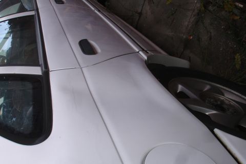 1990 Ford Taurus - Side profile of a white 1990 Ford Taurus, revealing its distinctive body lines and rear wheel.