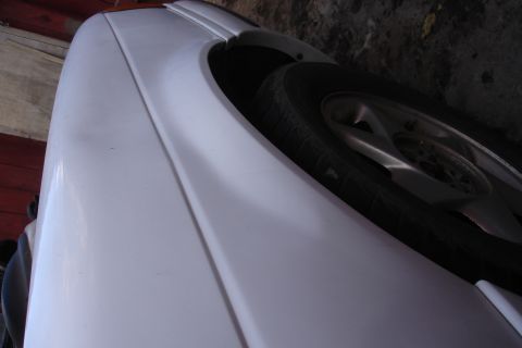 1990 Ford Taurus - Close-up of a car's fender and wheel, showing the tire and rim detail.
