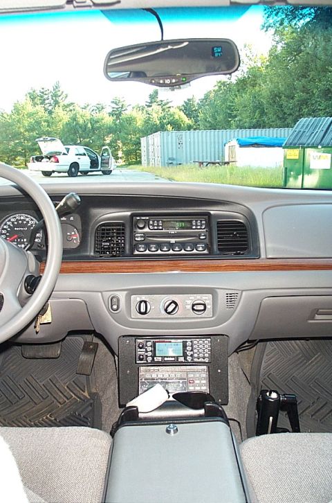 2001 Ford Crown Victoria - The interior of a 2001 Ford Crown Victoria, equipped with police radio equipment, shows a white Crown Victoria parked outside with its door…