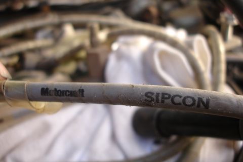 1990 Ford Taurus - A close-up shows a hose with 'Motorcraft' and 'SIPCON' markings, likely an engine component.