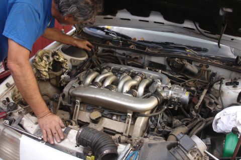 1990 Ford Taurus - Mechanic works on the intake manifold of a white 1990 Ford Taurus engine.