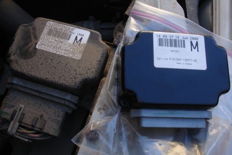 1990 Ford Taurus - Two engine control modules are shown, one older and dusty, the other newer and clean.