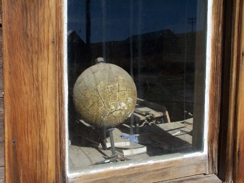1990 Ford Bronco - A weathered wooden sphere sits on a metal stand, viewed through a dusty window pane.