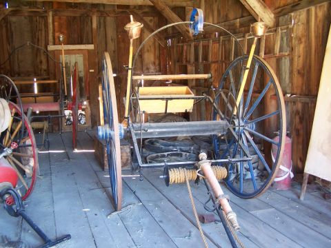 1990 Ford Bronco - An antique horse-drawn fire cart, likely from the late 19th or early 20th century, is stored in a rustic wooden structure.