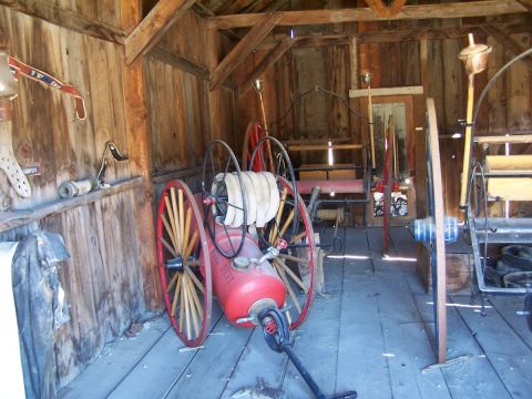1990 Ford Bronco - A vintage fire engine sits in a rustic wooden structure, surrounded by historical equipment.