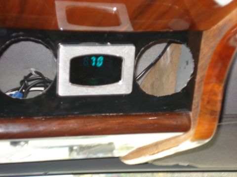 1992 Ford C-350 (Centurion Conversions) - Close-up of a digital gauge and wood-grain interior trim with empty circular openings.