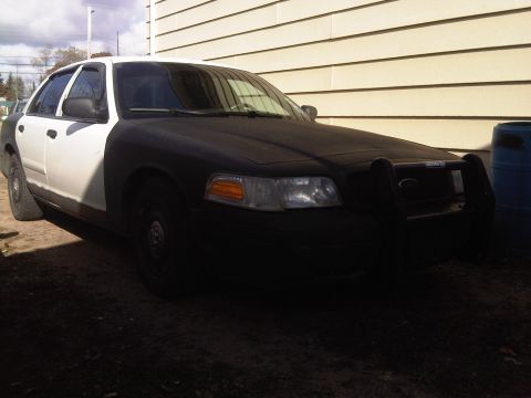 2003 Ford Crown Victoria - This 2003 Ford Crown Victoria police car, seen from a 3q-front angle, features a two-tone black and white paint scheme and a push bar.