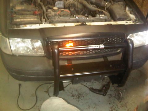 2003 Ford Crown Victoria - Front view of a 2003 Ford Crown Victoria police interceptor with its hood open and a push bar installed.