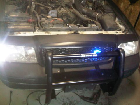 2003 Ford Crown Victoria - Front view of a 2003 Ford Crown Victoria showing the grille, push bar, and open engine bay.