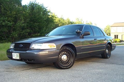 2001 Ford Crown Victoria - This Ford Crown Victoria is shown from a three-quarter front view, parked outdoors with trees and a building visible.
