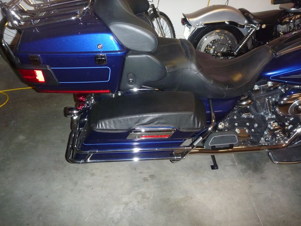 Blue motorcycle rear with saddlebags and chrome accents. Another motorcycle is visible behind it