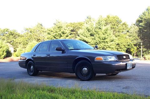 2001 Ford Crown Victoria - Dark gray 2001 Ford Crown Victoria, front 3/4 view, parked outdoors with a wooded area behind it.