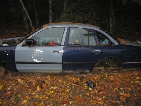 1991 Ford LTD Crown Victoria - Abandoned 1991 Ford Crown Victoria LTD sedan with mismatched paint sits in a wooded area.