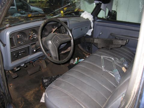 1991 Ford LTD Crown Victoria - The interior of a damaged vehicle shows a cracked windshield and worn seats, with another vehicle visible outside.