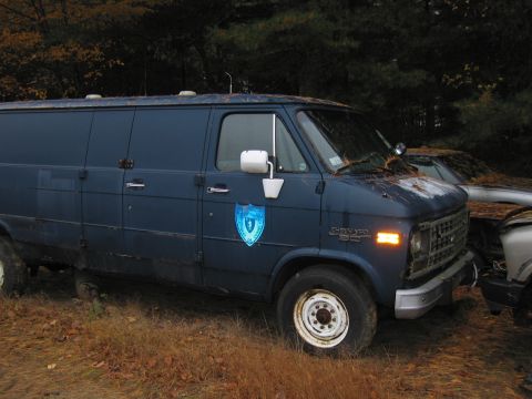 1991 Ford LTD Crown Victoria - A blue panel van sits in a yard with another vehicle partially visible beside it.