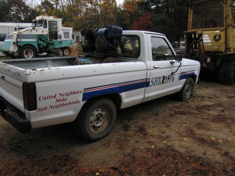 1991 Ford LTD Crown Victoria - A white pickup truck with "SHERIFF" text and a flat tire is parked next to other vehicles.
