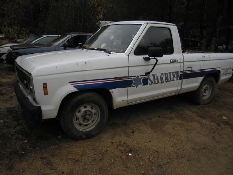 1991 Ford LTD Crown Victoria - A white pickup truck with "Sheriff" markings is parked outdoors, with other vehicles visible in the background.