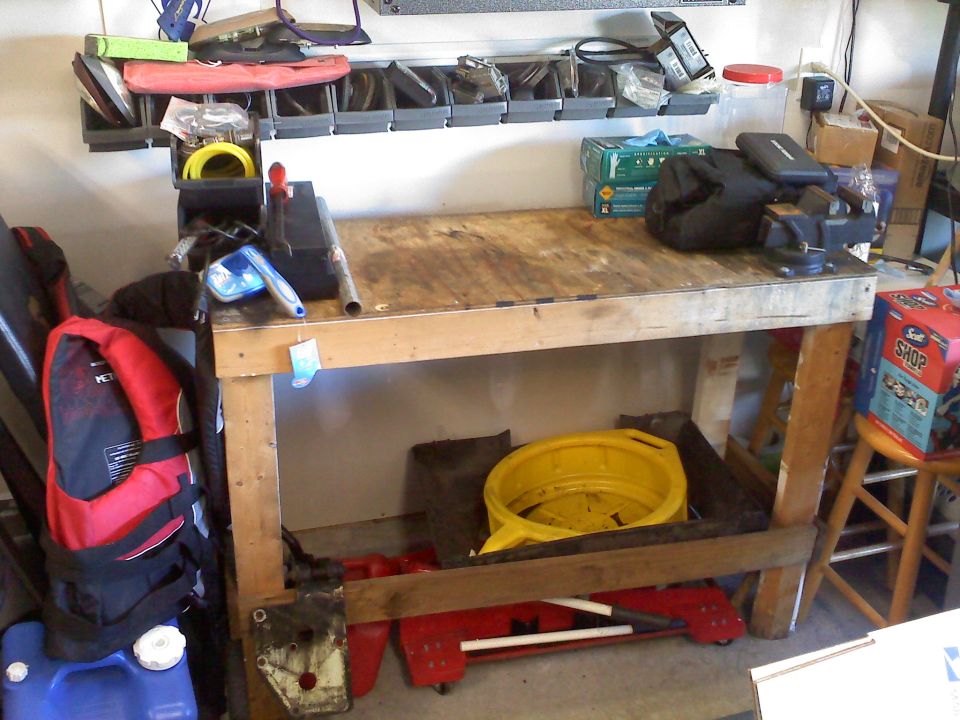 Workbench with tools, a yellow oil drain pan, and a blue plastic container