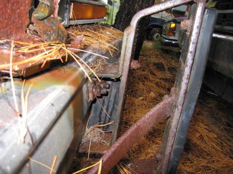 1991 Ford LTD Crown Victoria - Close-up of heavily rusted car parts and debris, with other vehicles visible in the background.