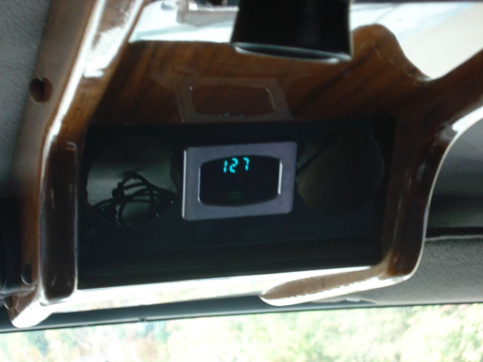 Vehicle interior with wood trim around a digital clock displaying 127