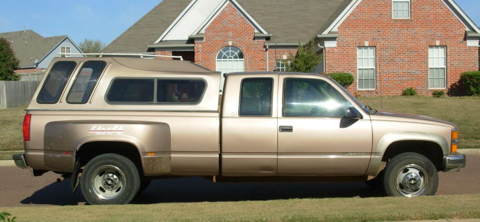 Tan Chevrolet dually pickup with camper shell side view