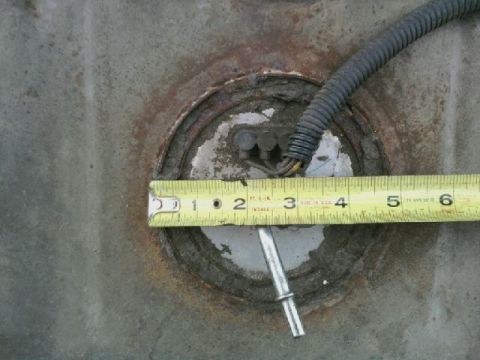 1995 Ford Bronco - A tape measure is used to measure the opening for a fuel pump sending unit on a vehicle's fuel tank.