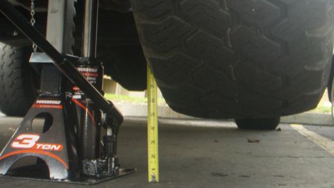 1995 Ford Bronco - A vehicle jack is positioned next to a tire, with a tape measure indicating height.