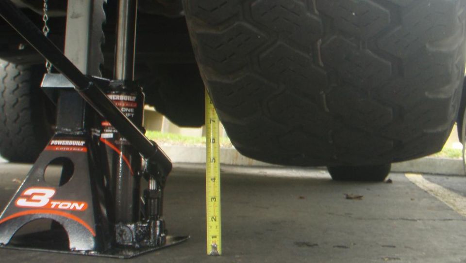 Vehicle jack and tape measure next to a tire