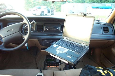 2001 Ford Crown Victoria - The interior of a 2001 Ford Crown Victoria is equipped with a laptop and radio, with another police car visible outside.