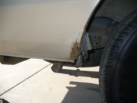 1986 Toyota Land Cruiser - Close-up of rust on a vehicle's lower body panel, with a tire visible on the right.