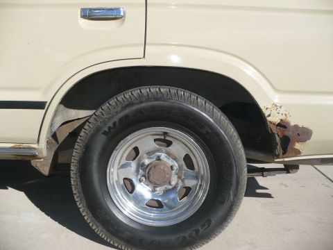 1986 Toyota Land Cruiser - Close-up of the rear wheel well and heavily rusted quarter panel on a 1986 Toyota Land Cruiser.