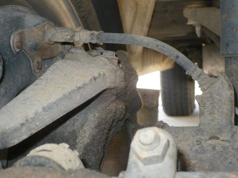 1986 Toyota Land Cruiser - Detail of vehicle's rear brake line and suspension components, showing rust and wear.