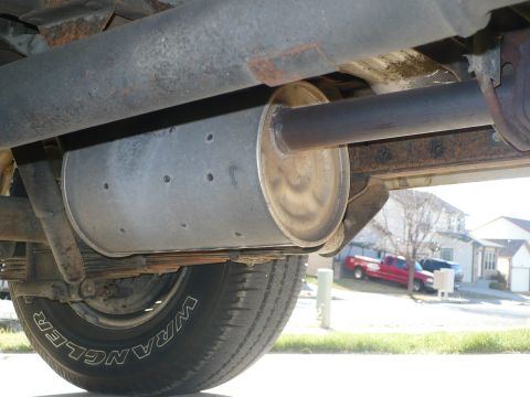 1986 Toyota Land Cruiser - A close-up of a vehicle's undercarriage shows the exhaust system and a tire, with other vehicles in the background.