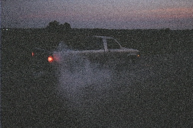 1988 Ford LTD Crown Victoria - Very grainy dusk photo of a car sliding sideways on a rural road with tire smoke rolling off the rear wheels and one red taillight glowing.…