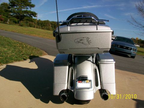 2009 Harley-Davidson FLH - Rear view of a silver motorcycle with an eagle decal on its saddlebag, parked on a driveway with a blue car behind it.
