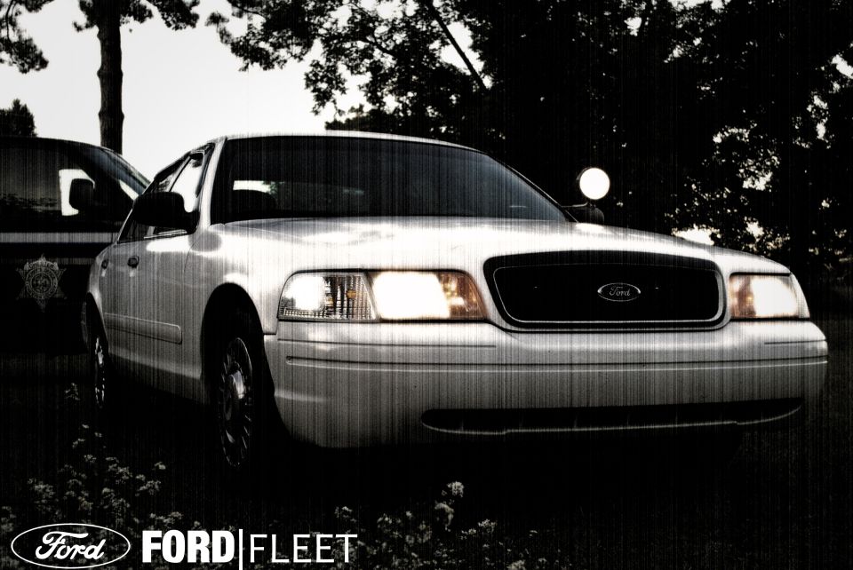 Front view of a white 2002 Ford Crown Victoria, parked next to another vehicle