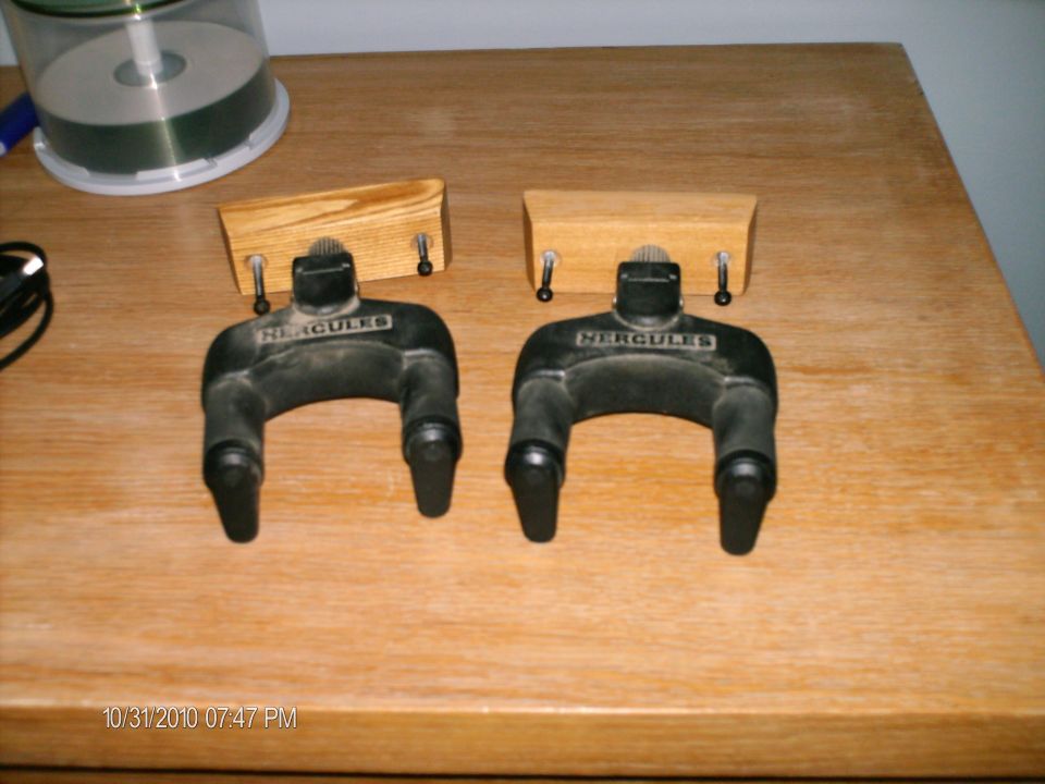 Two black Hercules guitar stands with wooden mounts on a table