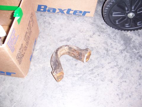 1992 Ford Bronco - A single rusted metal component rests on a concrete surface, accompanied by a cardboard box and a black wheel.
