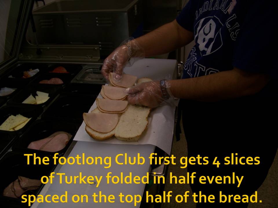 person making a footlong sandwich with turkey slices